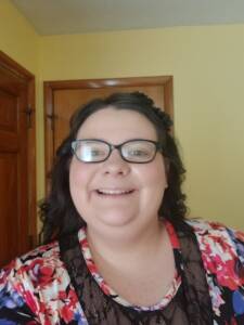 Head and shoulders photo of a smiling young woman with dark hair and glasses.