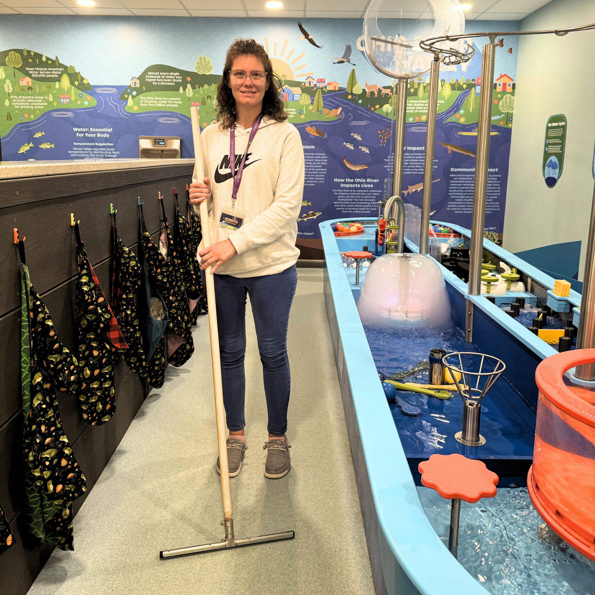 Woman holding a squeegee near a water table.